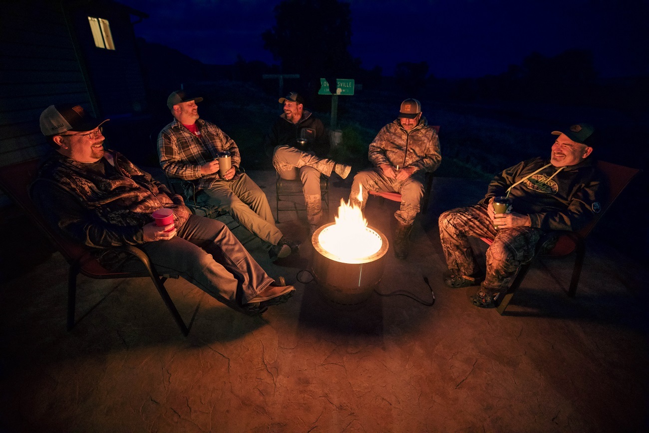 A group of hunters sit around a fire at night.